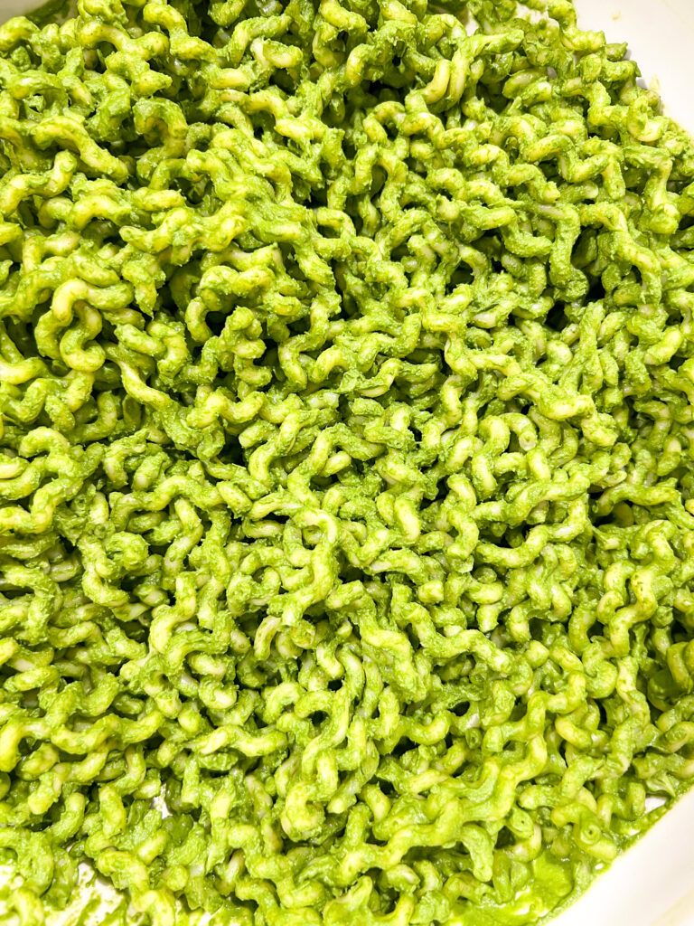 Close-up of green nutrient dense pasta for the whole family, coated in a creamy pesto sauce.