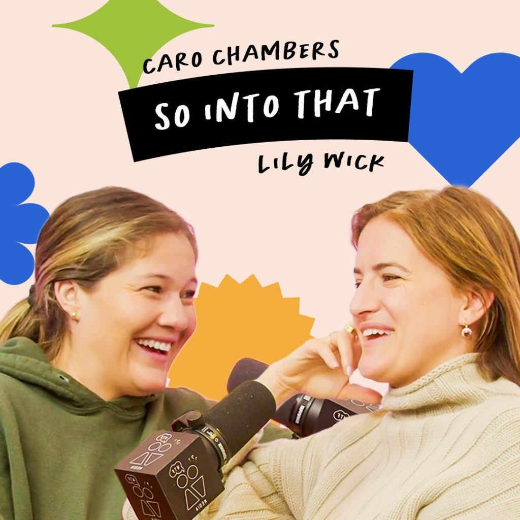 Two women sit closely, smiling and talking into microphones. The background has colorful shapes and text reads "Caro Chambers So Into That Lily Wick.